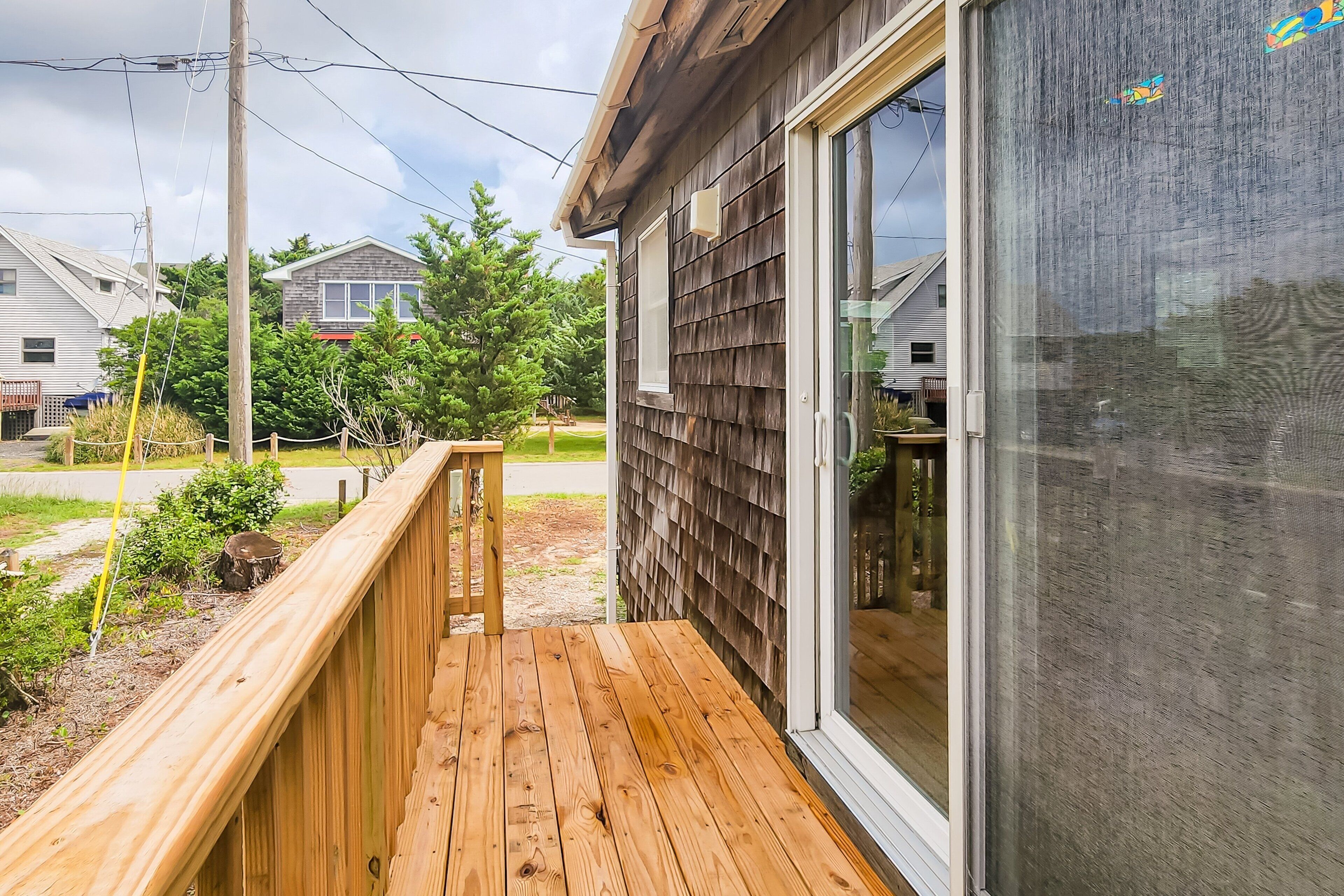 Une terrasse en bois avec une porte vitrée donnant sur un espace clos et protégé par des moustiquaires.