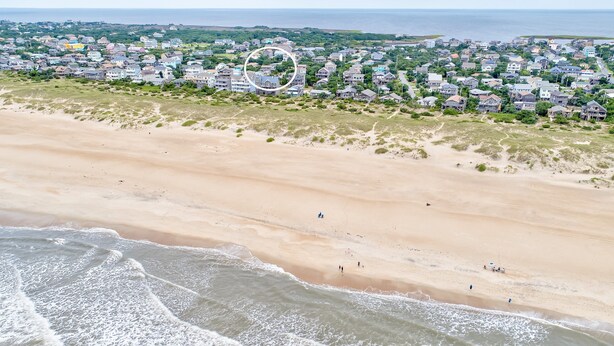 Eine Luftaufnahme einer Küstenwohngegend mit Häusern, einem Strand und dem Meer.