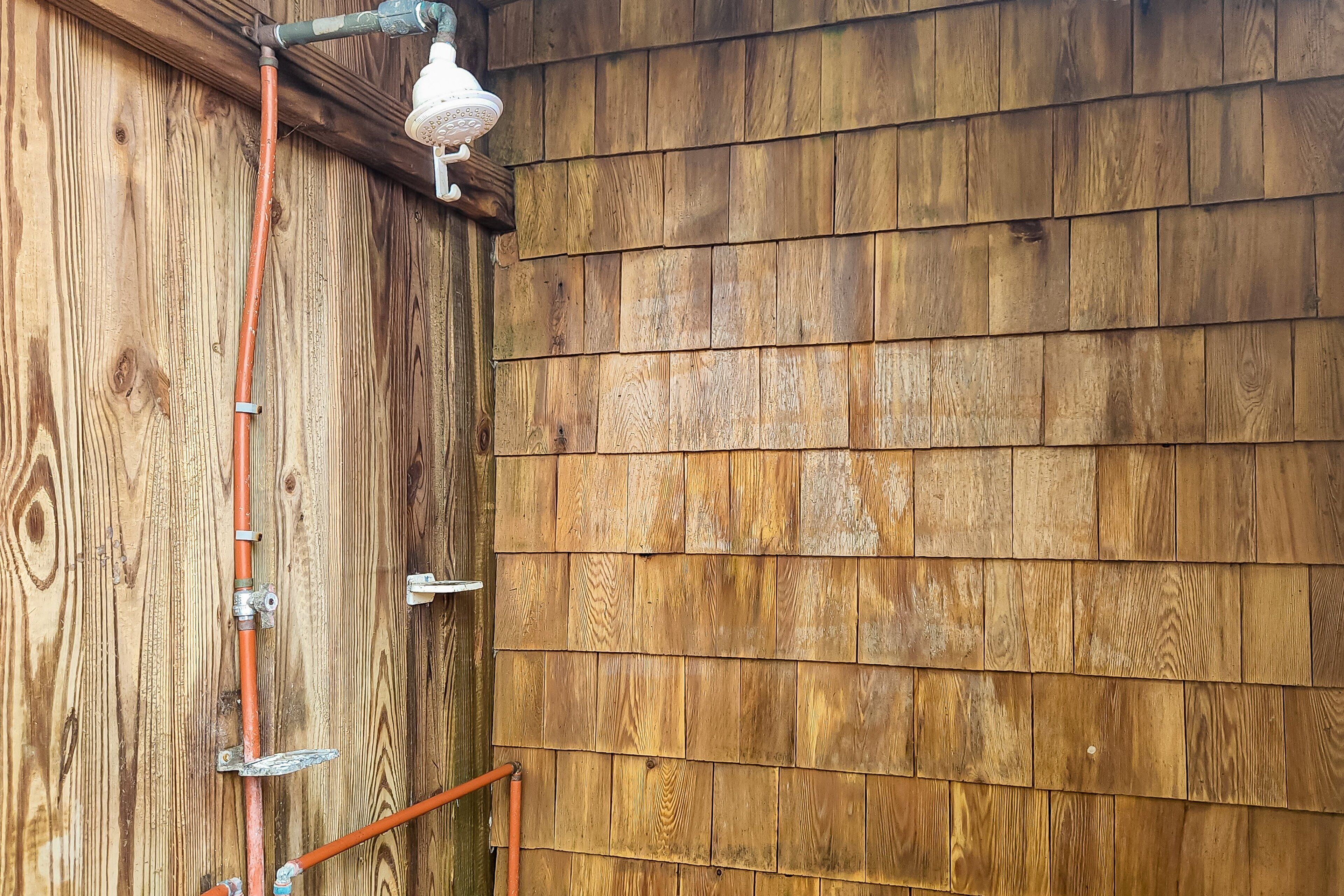 A wooden exterior wall with a metal pipe and a white fixture.