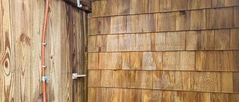 A wooden exterior wall with a metal pipe and a white fixture.