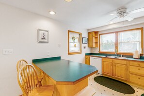 A kitchen with wooden cabinets, a green countertop, a window with blinds, and a ceiling fan.
