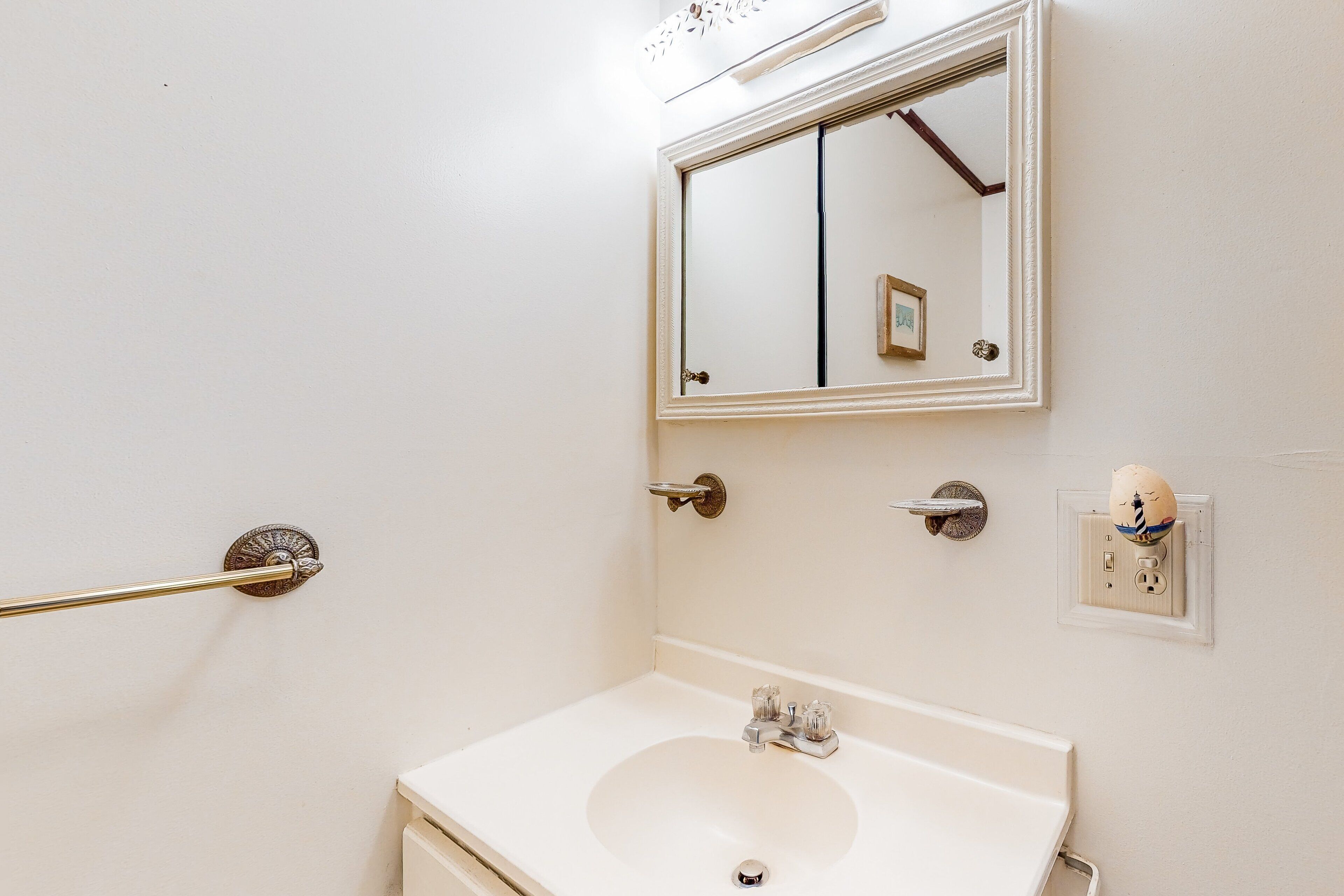 A bathroom with a white sink, a mirror, and a towel rack.