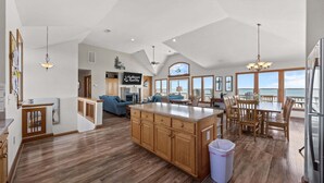 A spacious kitchen with a large island, wooden cabinets, and a dining area with a view. - Oceanfront house with private pool, hot tub, & washer/dryer (Avon)
