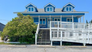 Un bâtiment à deux étages, à l’extérieur bleu et aux ornements blancs, doté d’un escalier menant à un porche agrémenté d’une balustrade.