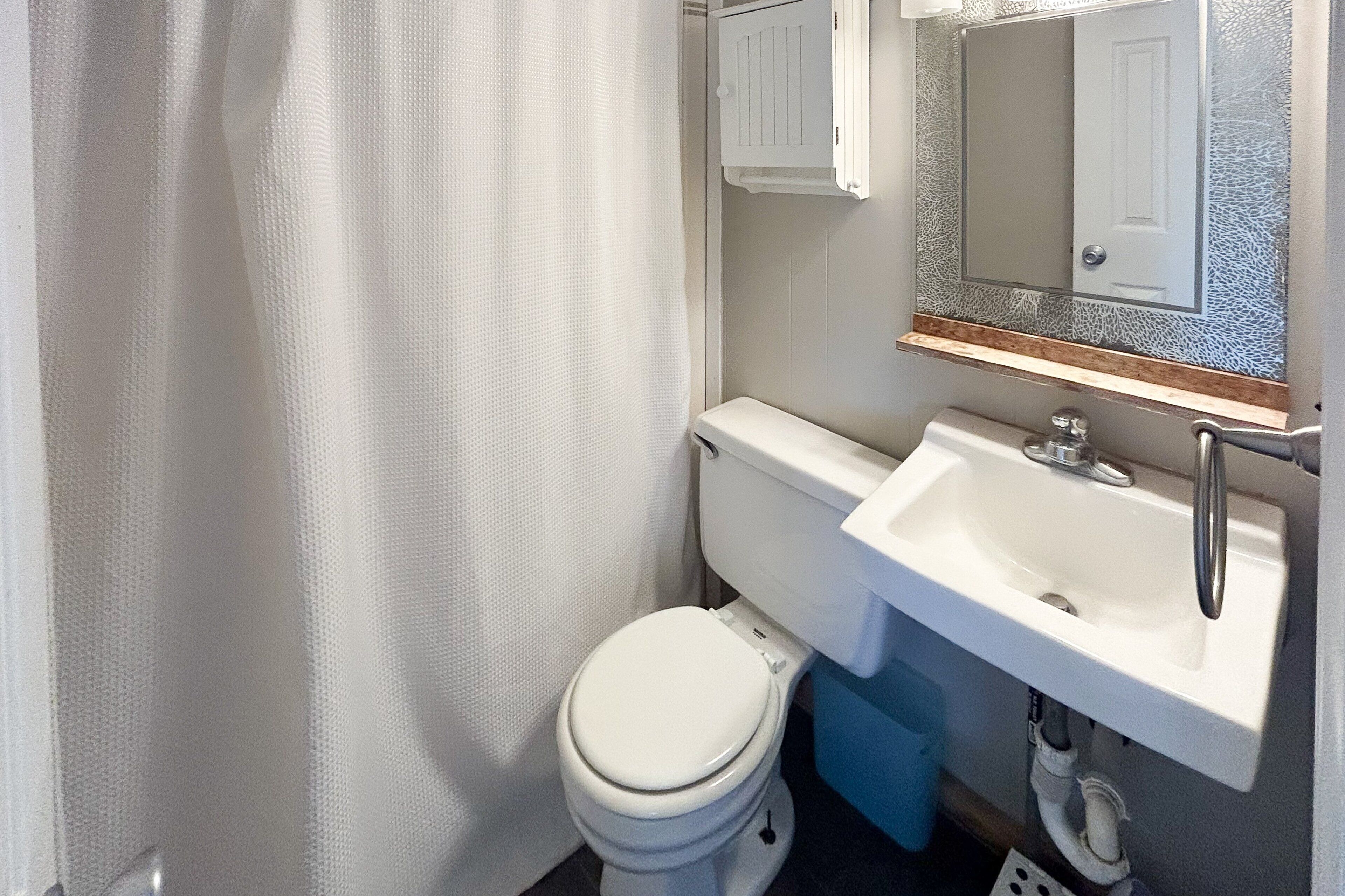 A small bathroom with a toilet, sink, and mirror.