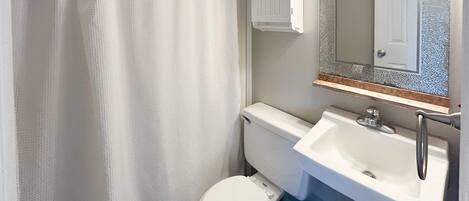 A small bathroom with a toilet, sink, and mirror.