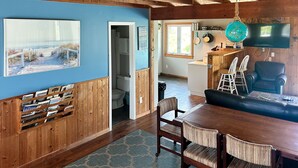 Un intérieur en bois comprenant un coin repas, un téléviseur et une vue sur la plage.
