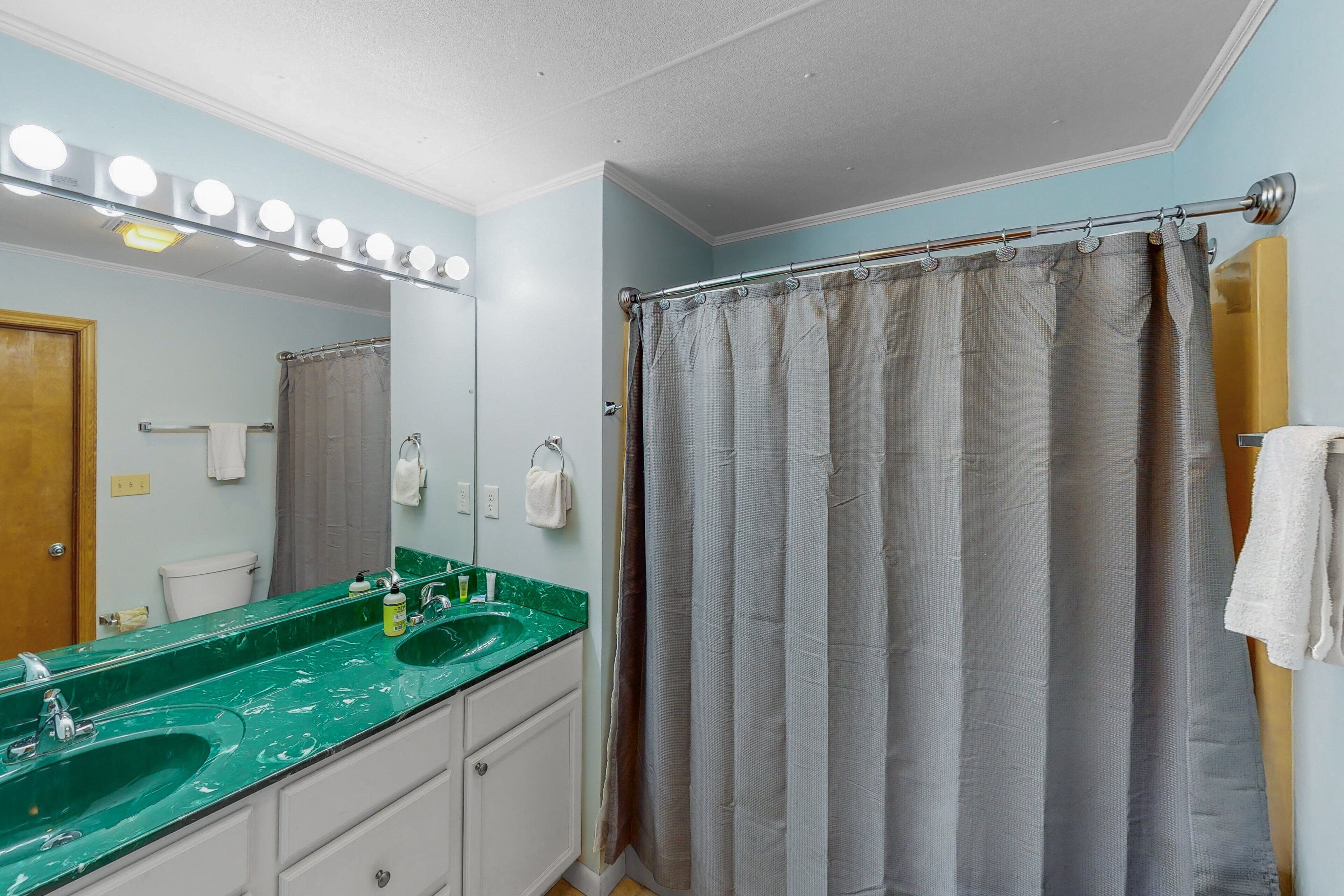 Une salle de bain avec deux lavabos, un miroir et un rideau de douche.