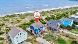 A coastal property with a beach view, featuring a blue house with a staircase leading to a deck, a light blue house, and a blue building with a dock. - Sand Dollar #13-HC: Oceanfront, Dog-Friendly, Private Hot Tub (Avon)