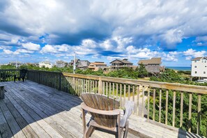 A wooden deck with a single Adirondack chair, overlooking a residential area with houses and a view of the ocean. - Lovely home with ocean view, beach access, pool, hot tub, & W/D - dog-friendly (Avon)