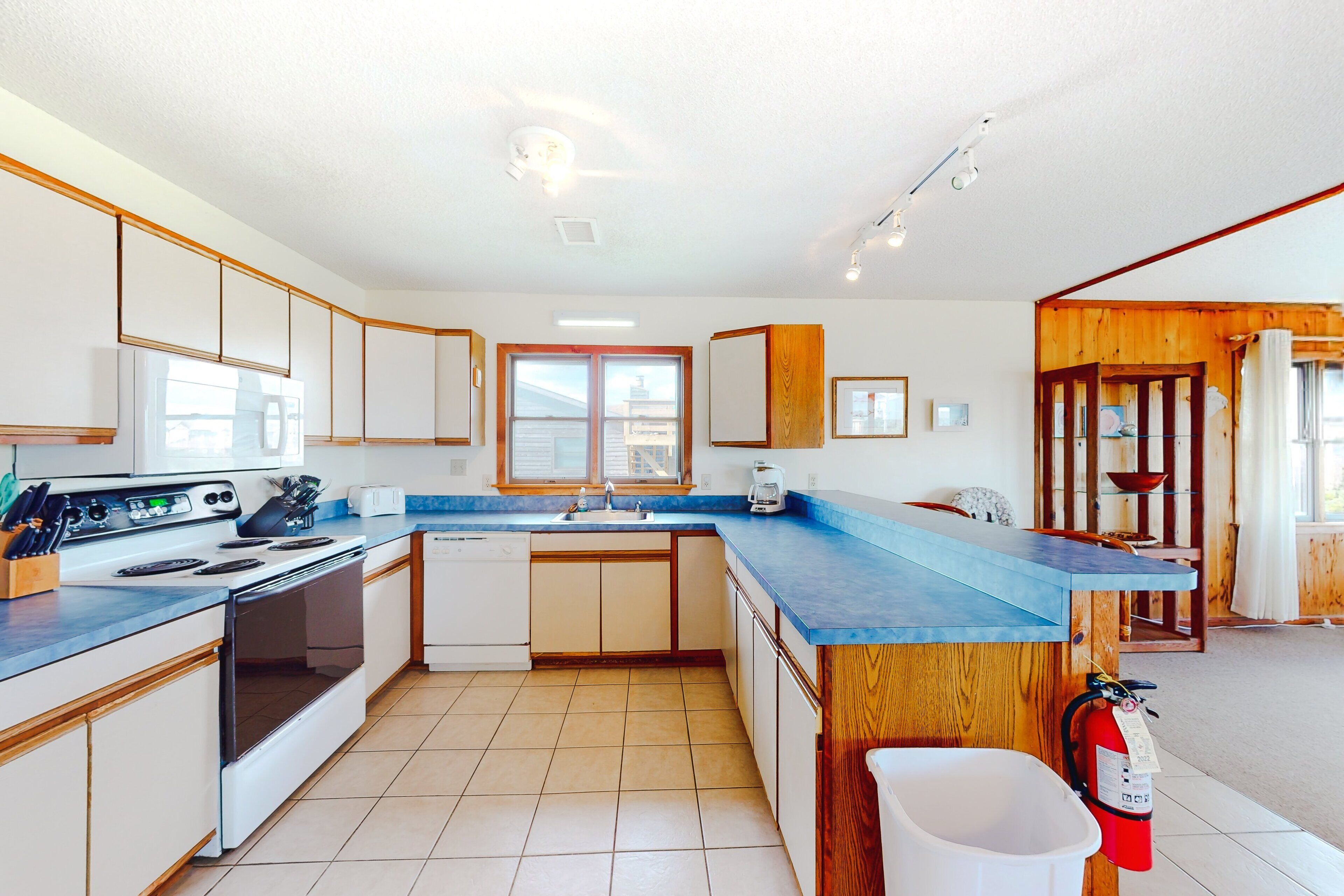 Una cocina moderna con una isla central, electrodomésticos integrados y un ventanal grande.