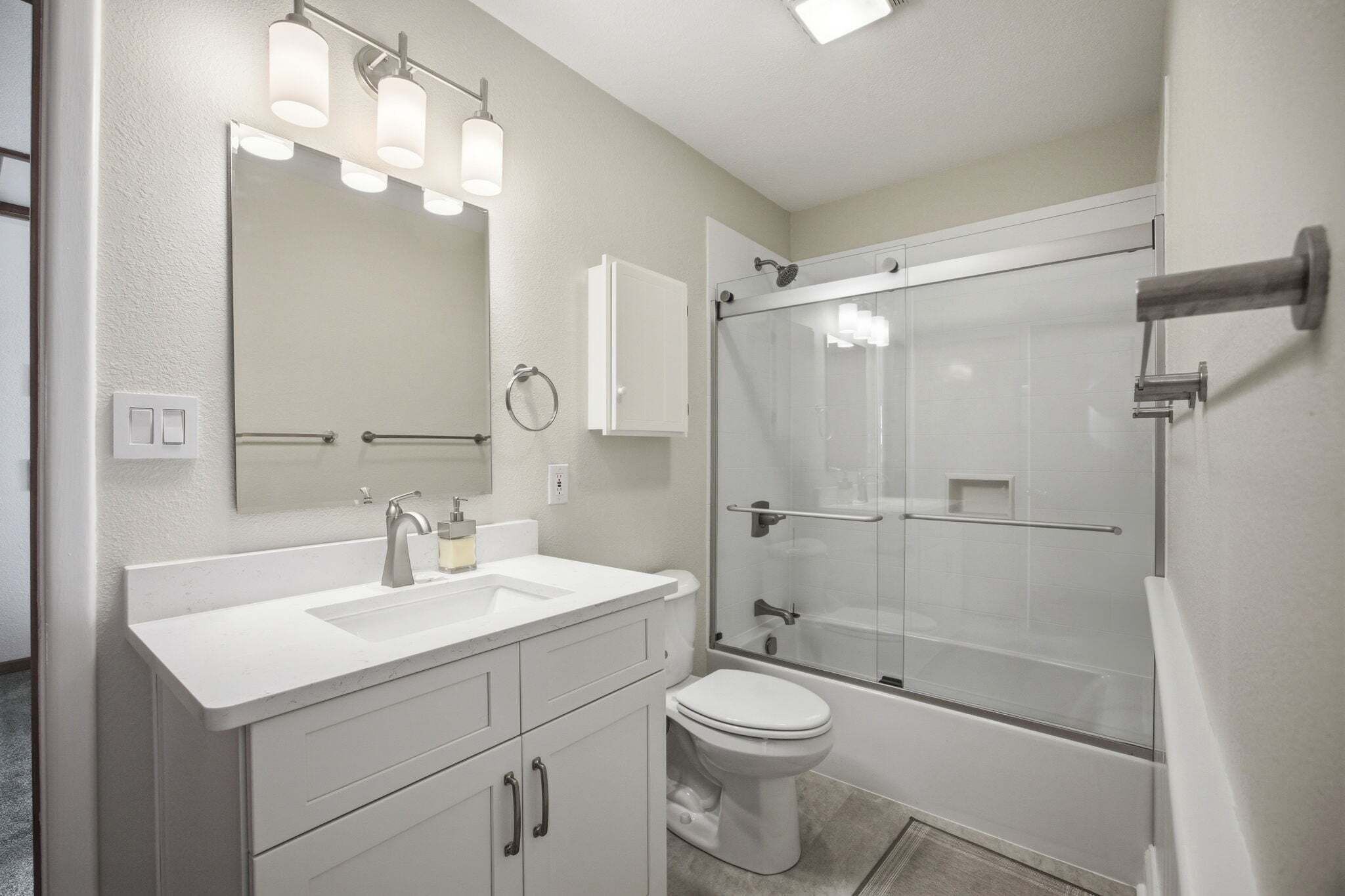 A modern bathroom with a sink, toilet, and glass-enclosed shower.
