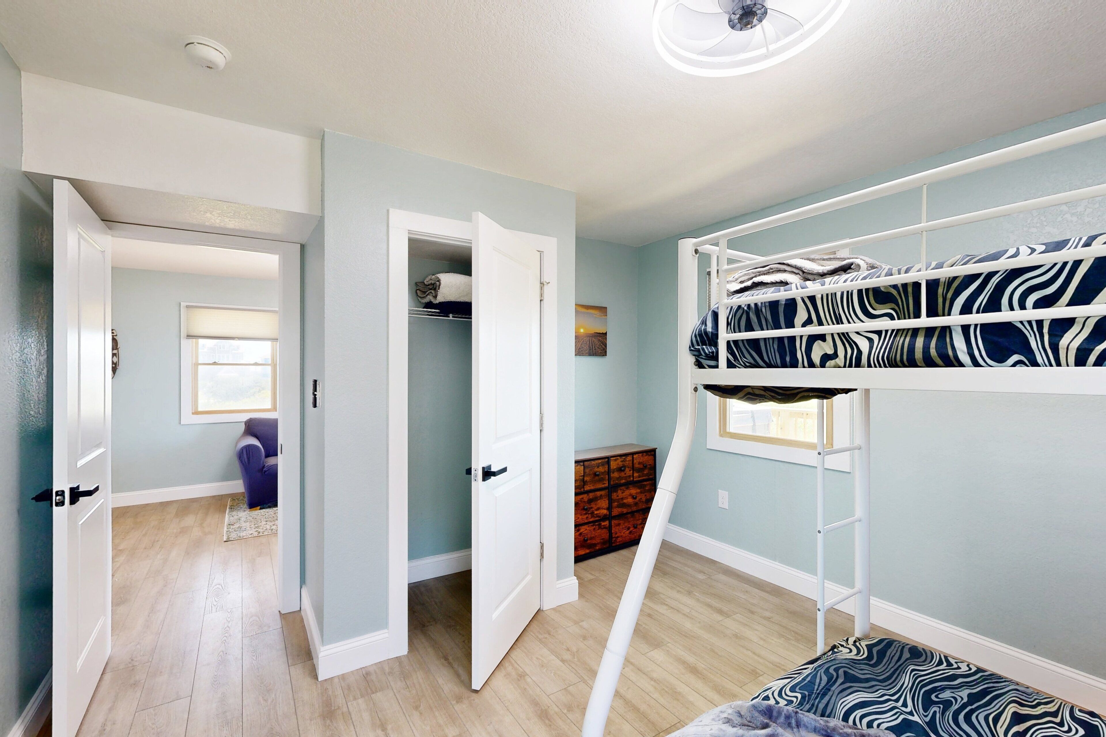 A room with a bunk bed, a closet, and a window.