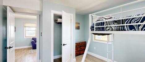A room with a bunk bed, a closet, and a window.