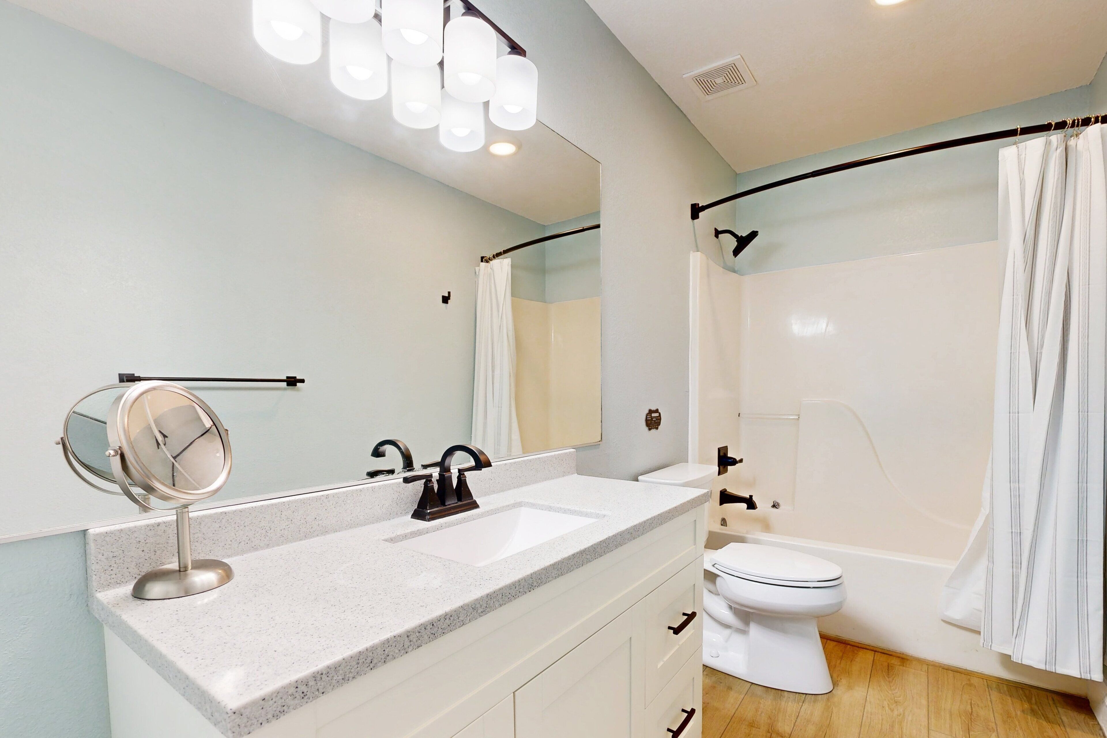 A modern bathroom with a white sink, a mirror, a toilet, and a shower area.
