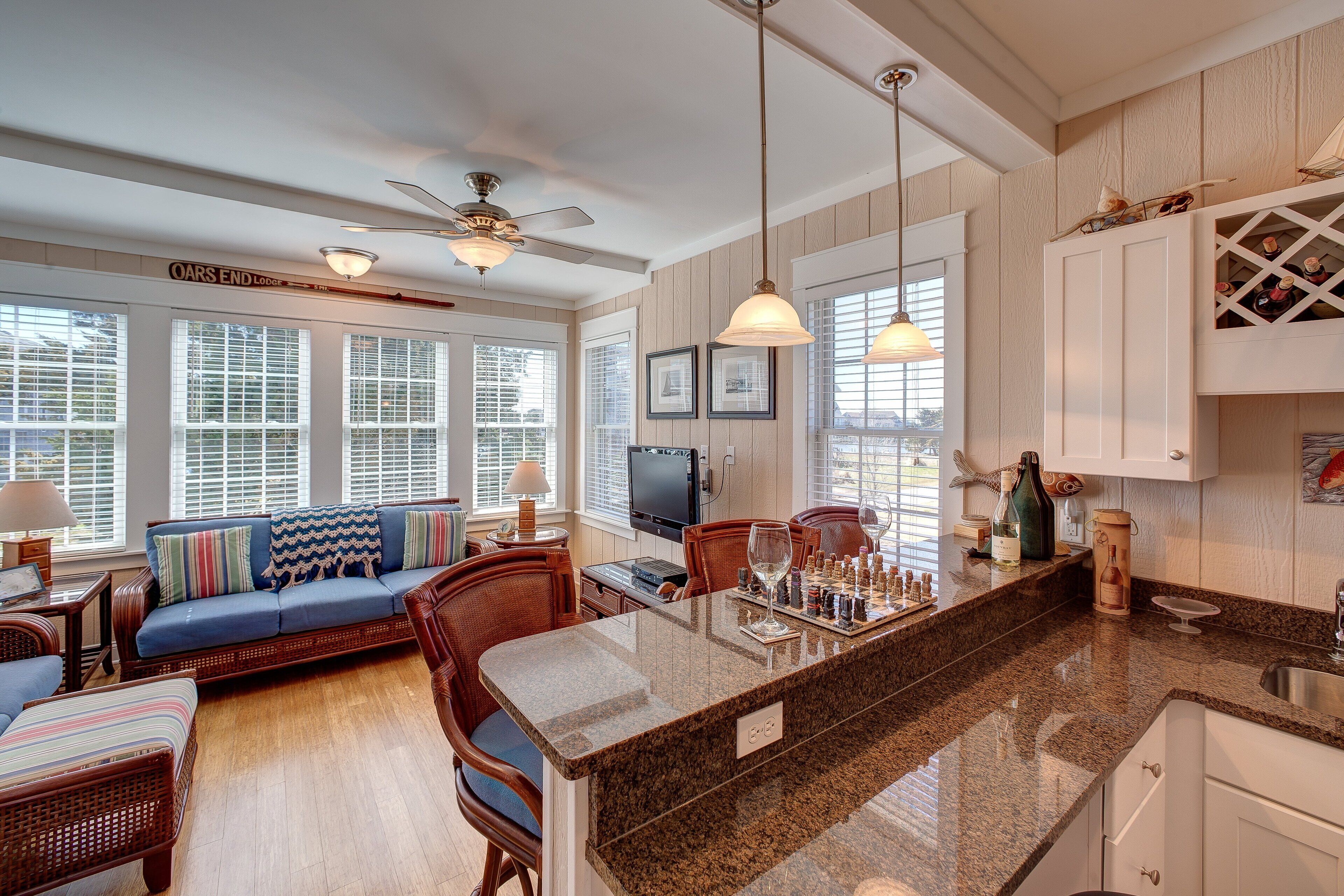 A spacious living area with a large sofa, a dining table, and a kitchen island with a chessboard.