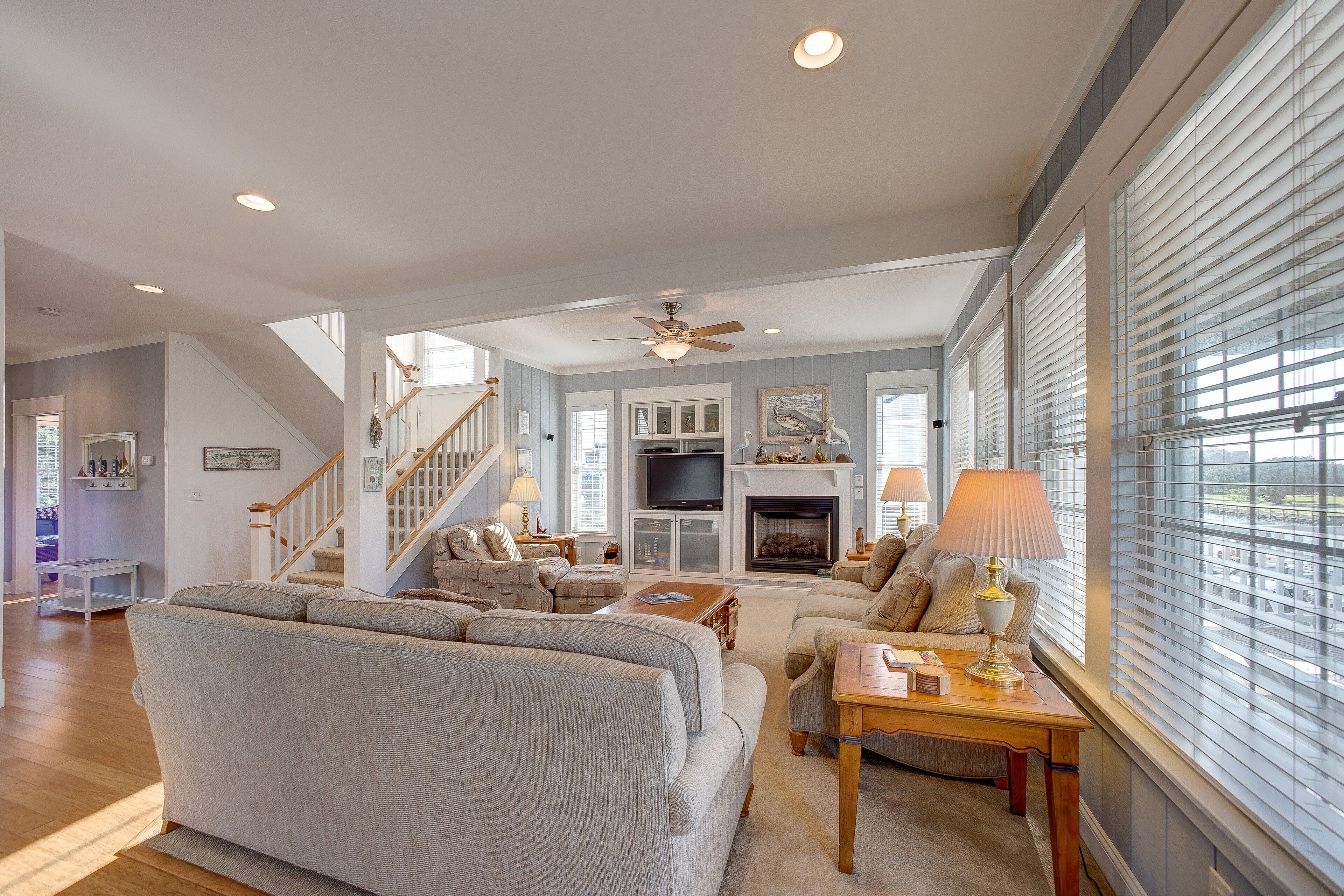 A spacious living room with a fireplace, comfortable seating, and a staircase leading to an upper floor.