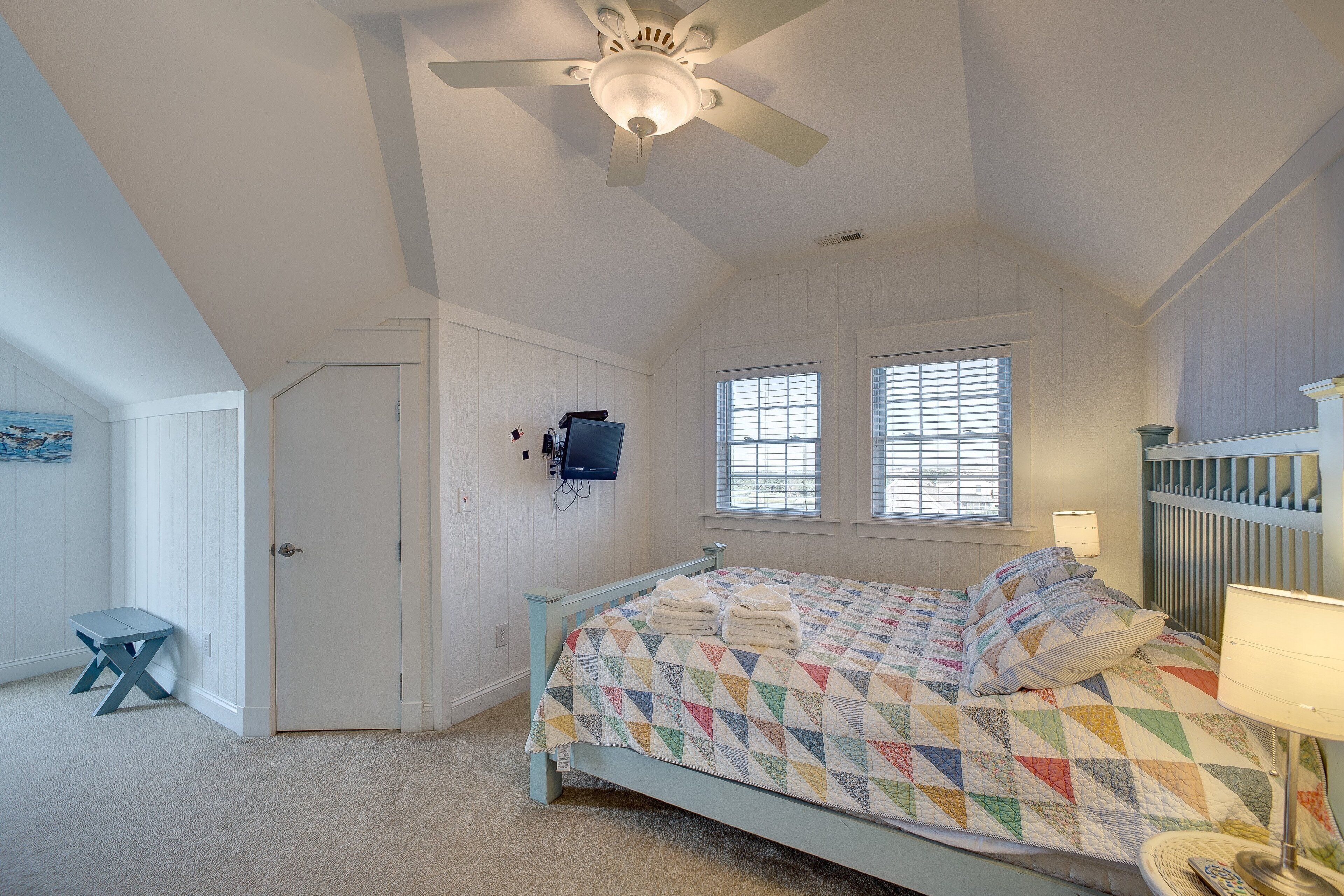 A bedroom with a bed, a ceiling fan, a window, and a door.