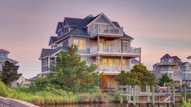A multi-story waterfront house with balconies, a dock, and a river view. - Huge, canal-front home w/private hot tub, WiFi, central AC, washer & dryer, dock (Frisco)