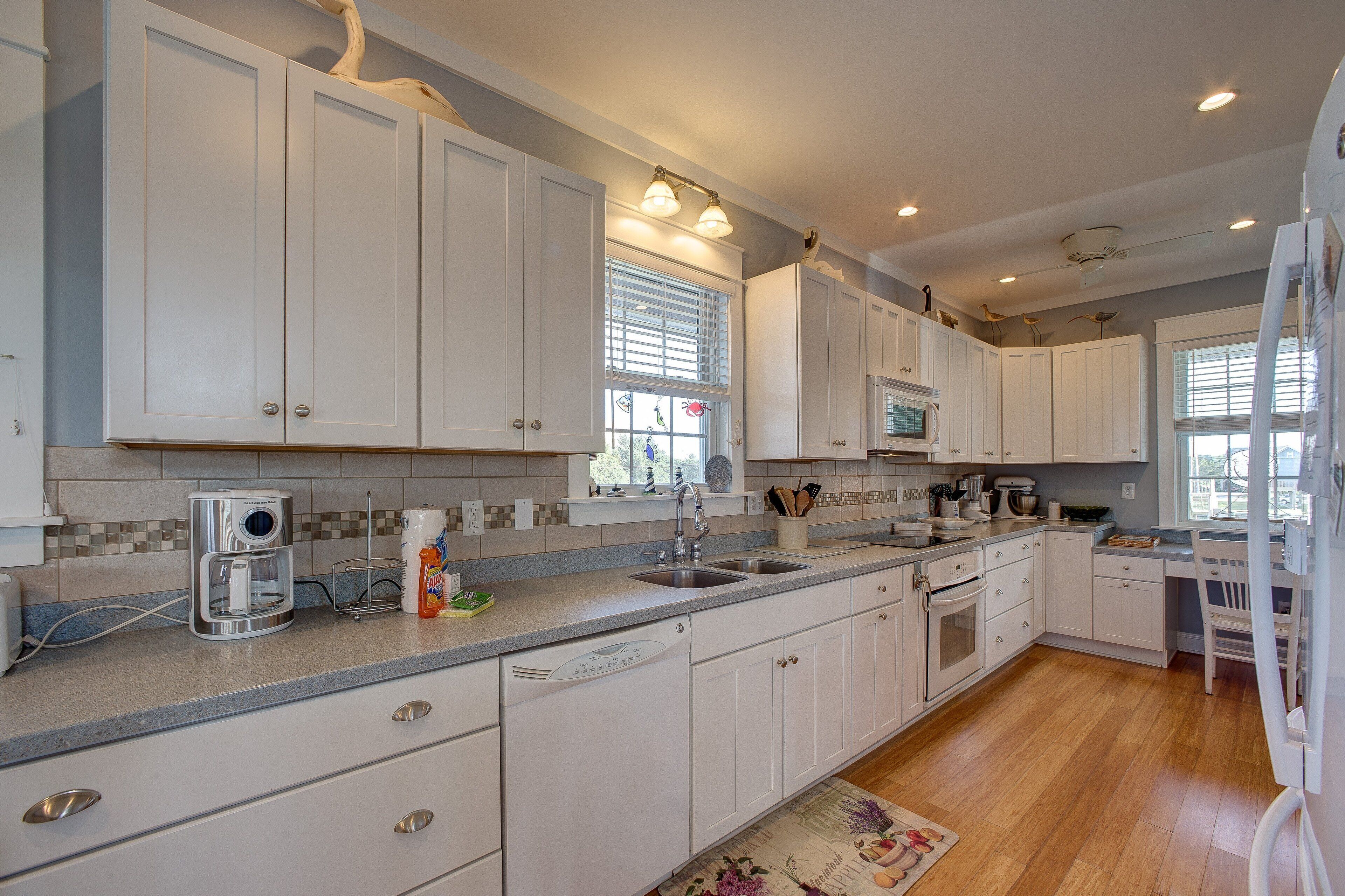 A modern kitchen with white cabinetry, a built-in oven, and a large island with a sink.
