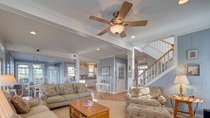A spacious living room with a ceiling fan, a wooden coffee table, and two patterned armchairs. - Huge, canal-front home w/private hot tub, WiFi, central AC, washer & dryer, dock (Frisco)