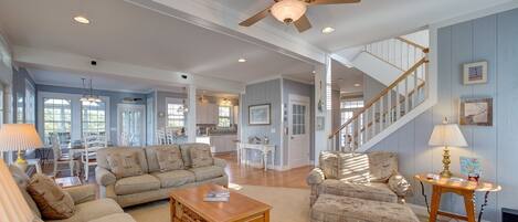 A spacious living room with a ceiling fan, a wooden coffee table, and two patterned armchairs.
