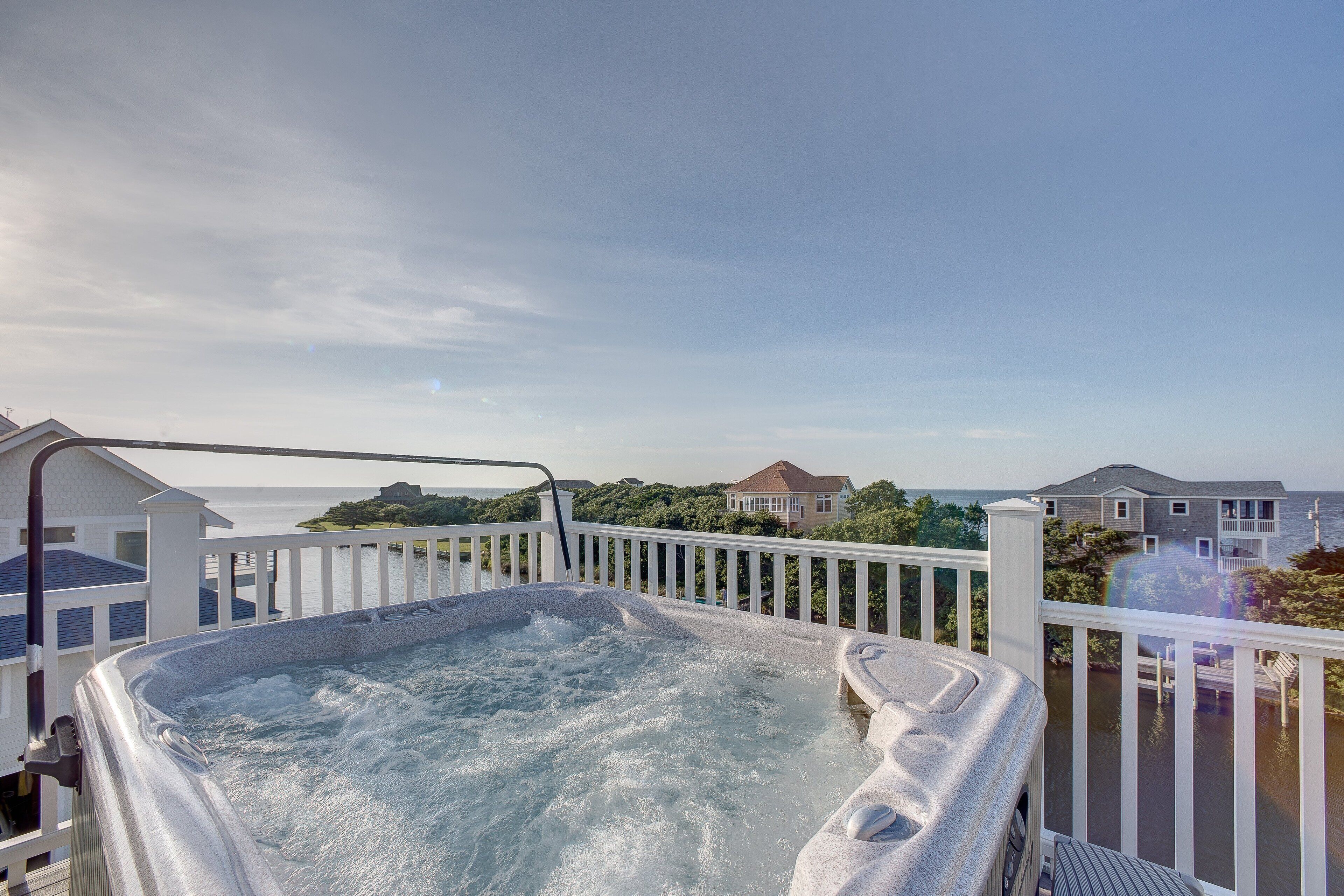 A hot tub on a deck with a view of houses and water.