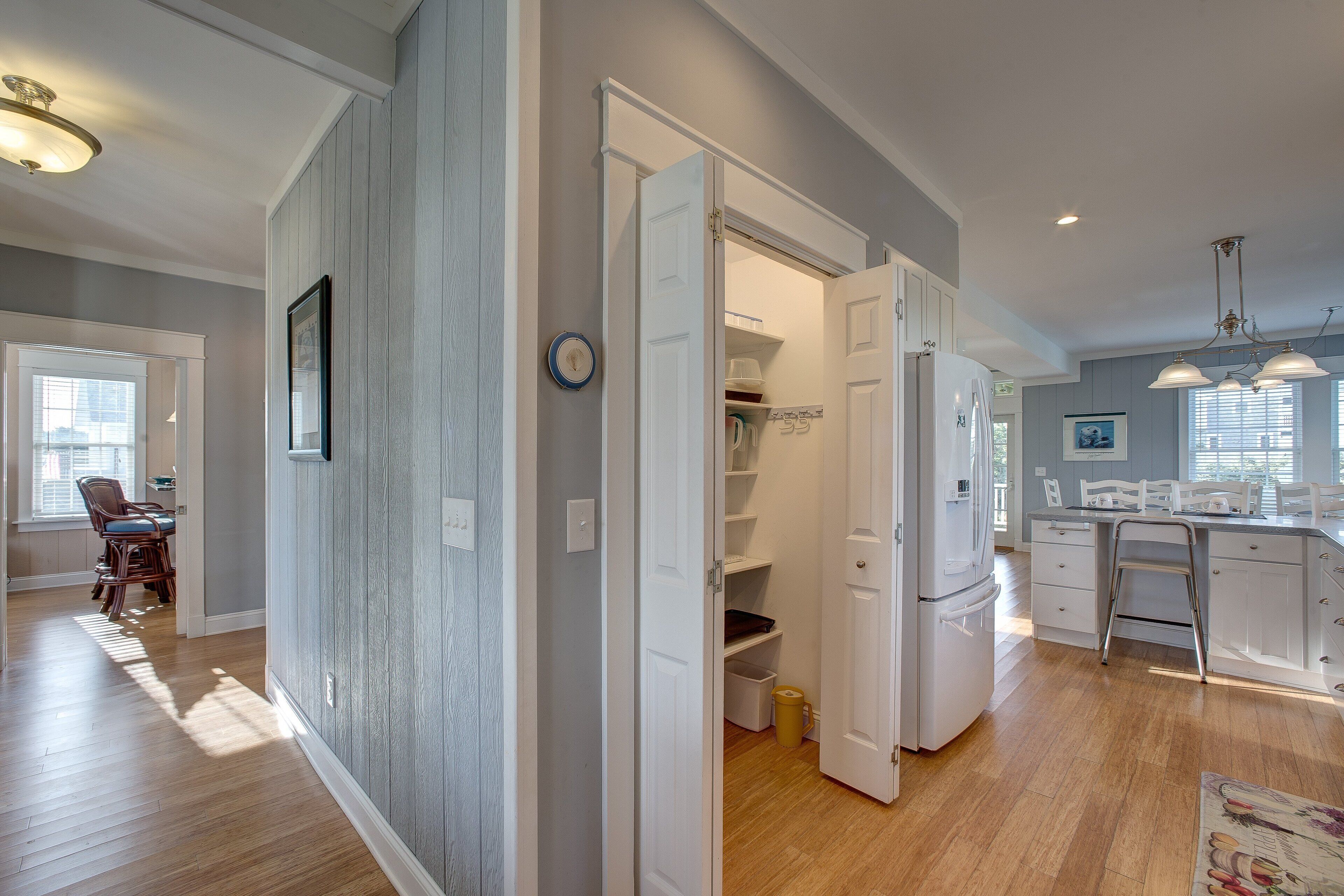 Una cocina moderna con armarios blancos, un refrigerador de acero inoxidable y un comedor con mesa y sillas.