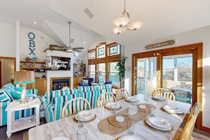A dining area with striped furniture, a fireplace, and a view of the outdoors.