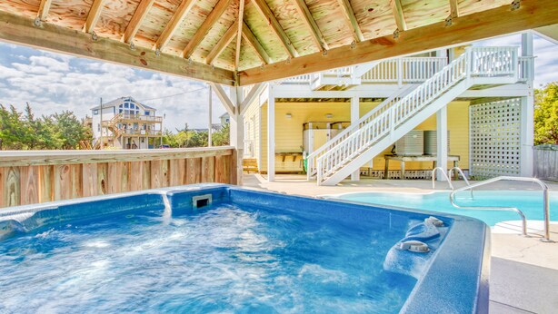 A hot tub with a wooden deck and a pool in the background. - Spacious dog-friendly haven with private pool, hot tub, pool table, & AC (Avon)