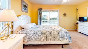 A bedroom with a bed, a ceiling fan, a window with curtains, a bedside table with a lamp, and a dresser. - Spacious dog-friendly haven with private pool, hot tub, pool table, & AC (Avon)