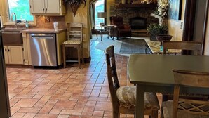 A spacious kitchen with modern appliances, a dining area with a table and chairs, and a stone fireplace. - Homestead Hideaway (Sentinel)