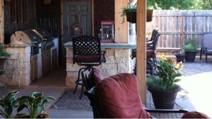 An outdoor patio with a grill, chairs, and potted plants. - Homestead Hideaway (Sentinel)