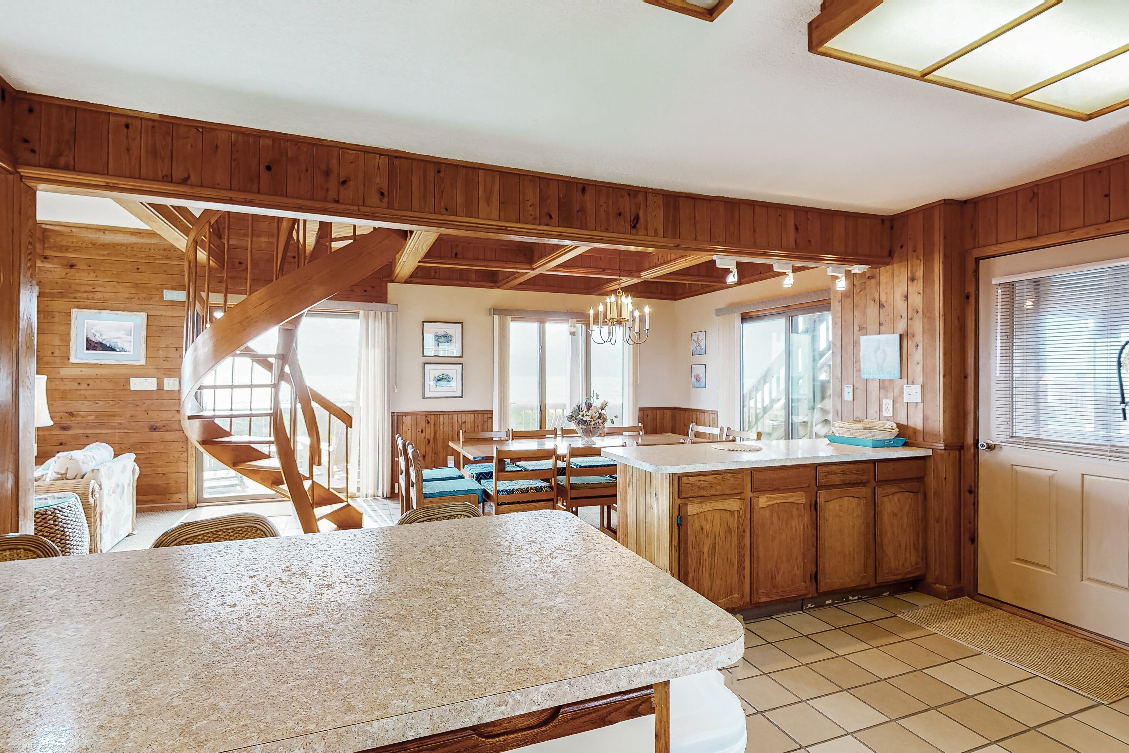A spacious kitchen with wooden cabinets, a granite countertop, and a dining area with a wooden table and chairs.