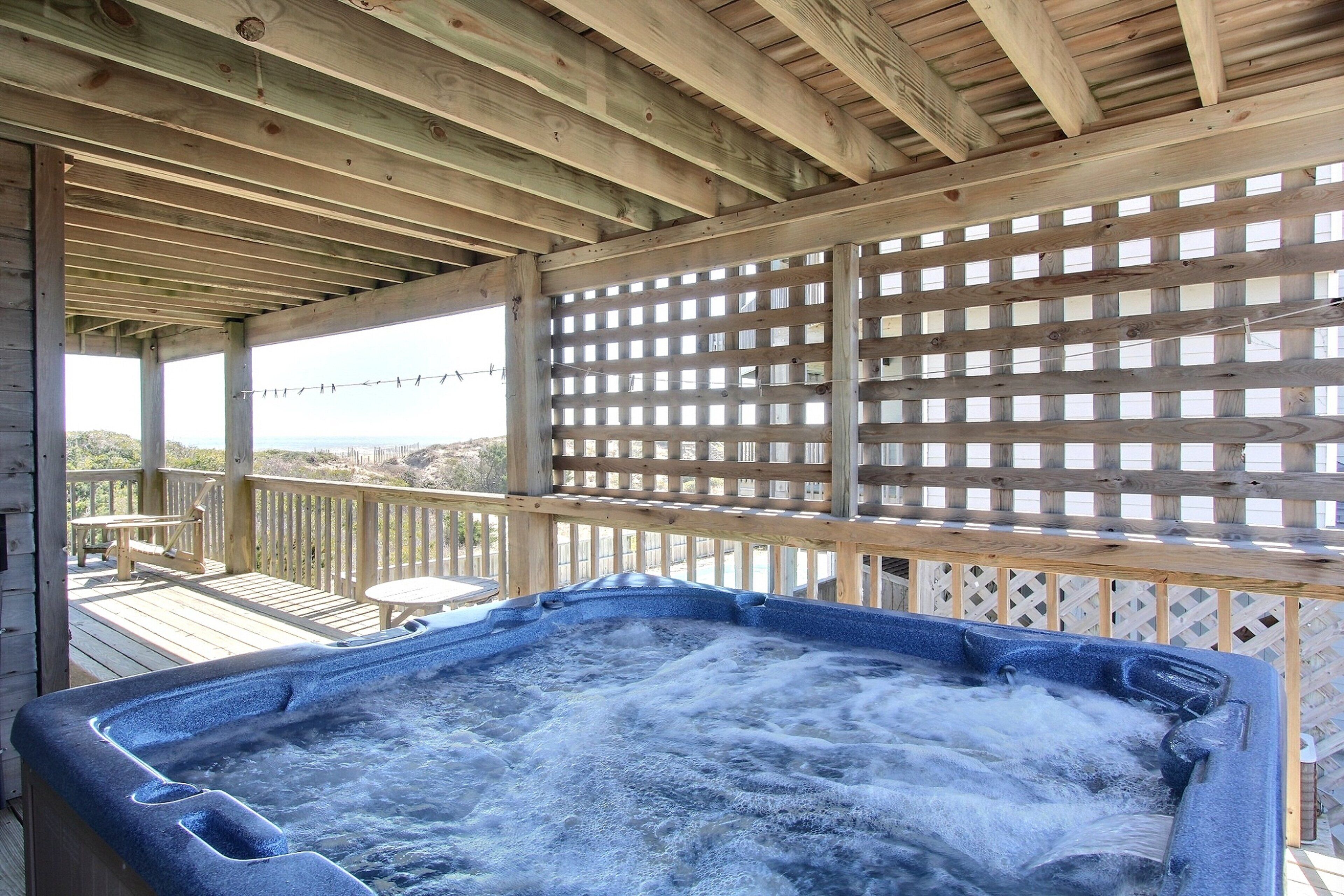 A hot tub on a wooden deck with a view of the ocean.