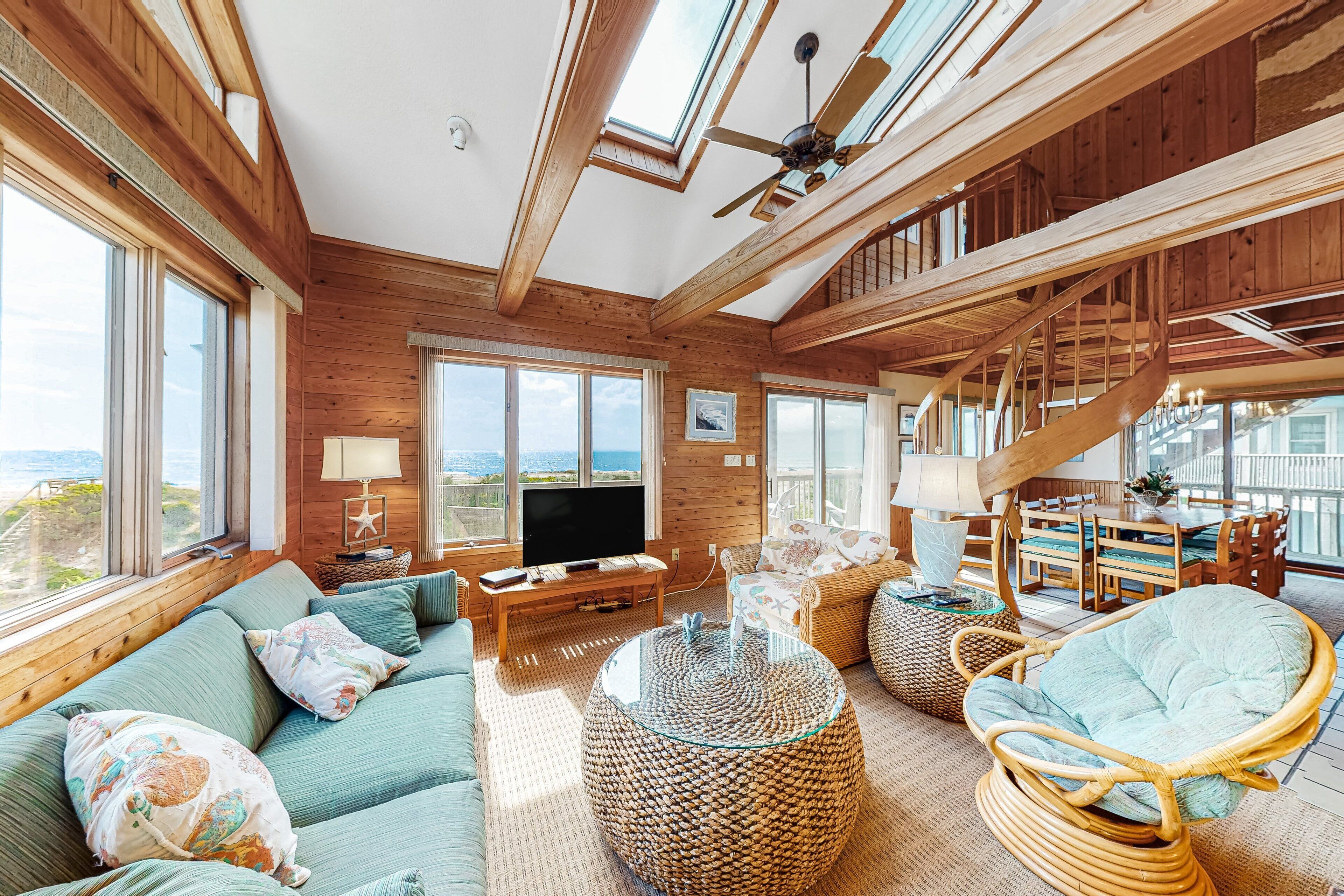 A spacious living room with a large TV, comfortable seating, and a staircase leading to an upper level.