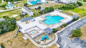 An aerial view of a residential area with a swimming pool, a playground, and a tennis court. - Reel Paradise: Steps From Canal w/Screened-in Porch (Avon)