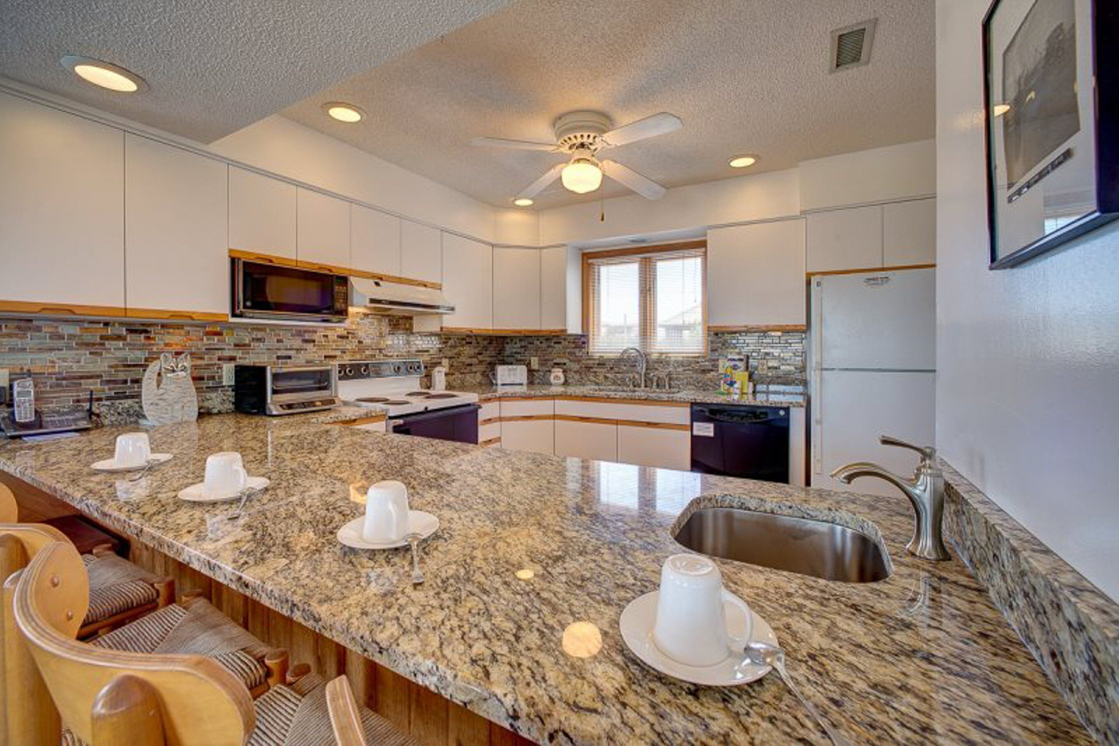 A modern kitchen with granite countertops, a built-in microwave, and a large island with seating.