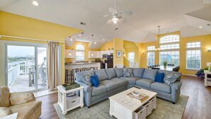 A spacious living area with a grey sectional sofa, a white coffee table, and a balcony with a sliding door.