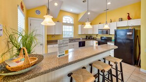 A kitchen with a central island, bar stools, and a refrigerator.