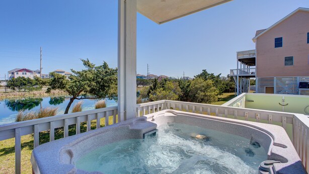 A hot tub with a view of a lake and houses in the background.