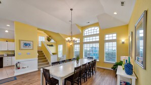 A spacious kitchen with a large island, wooden flooring, and a staircase leading to an upper level.