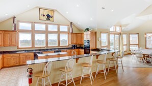A spacious kitchen with wooden cabinets, a large island with bar stools, and a view of the city through large windows.
