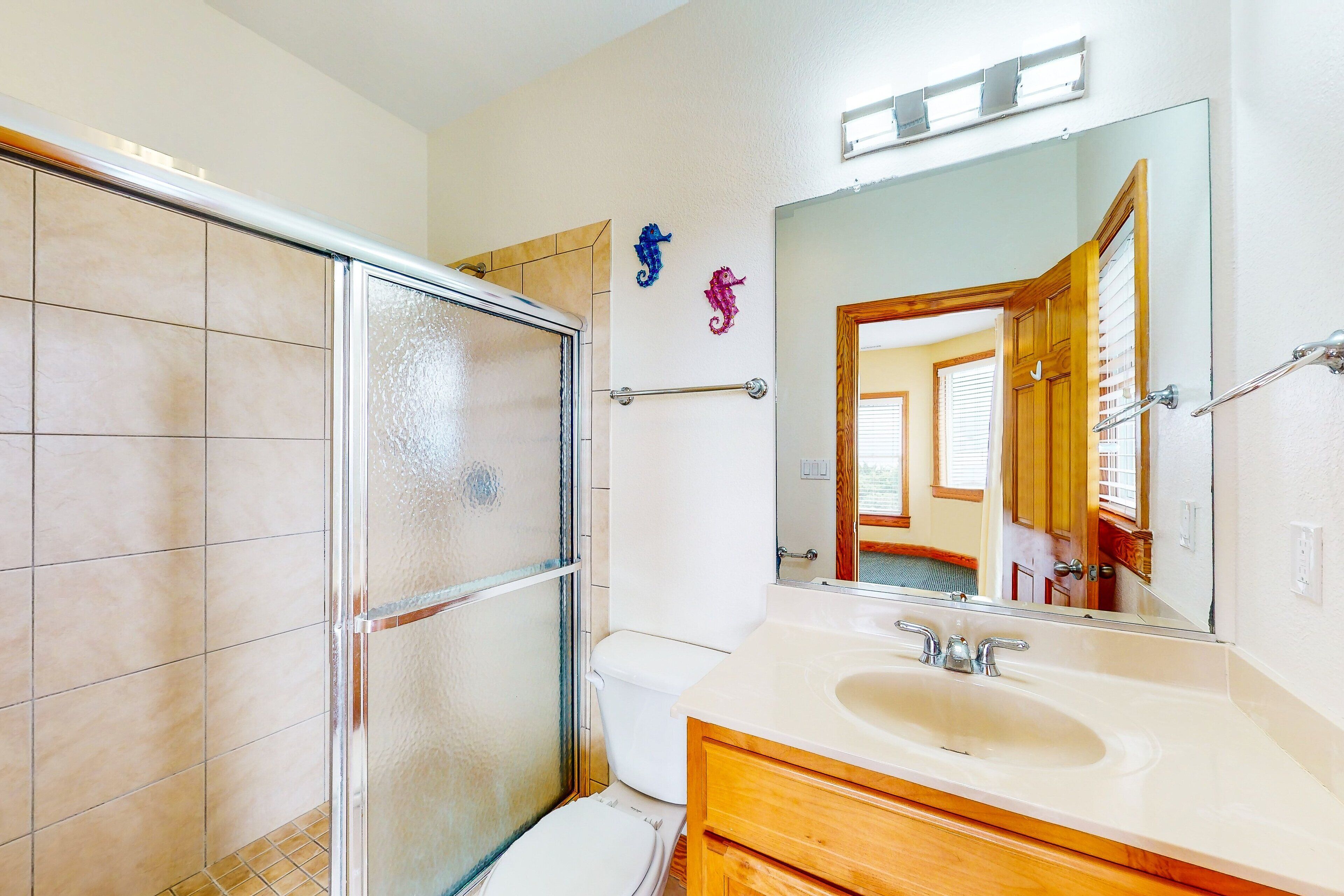 A bathroom with a glass shower enclosure, a white toilet, and a vanity with a mirror.