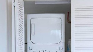 A compact laundry room with a washer and dryer stacked vertically. - Forest Cabin w/ Stunning Wall of Windows (Jackson)