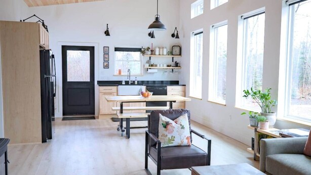 A modern kitchen with a dining area, a sofa, and a window with a view. - Forest Cabin w/ Stunning Wall of Windows (Jackson)