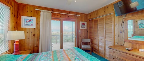 Une chambre avec un lit, une commode, une télévision et un balcon offrant une vue.