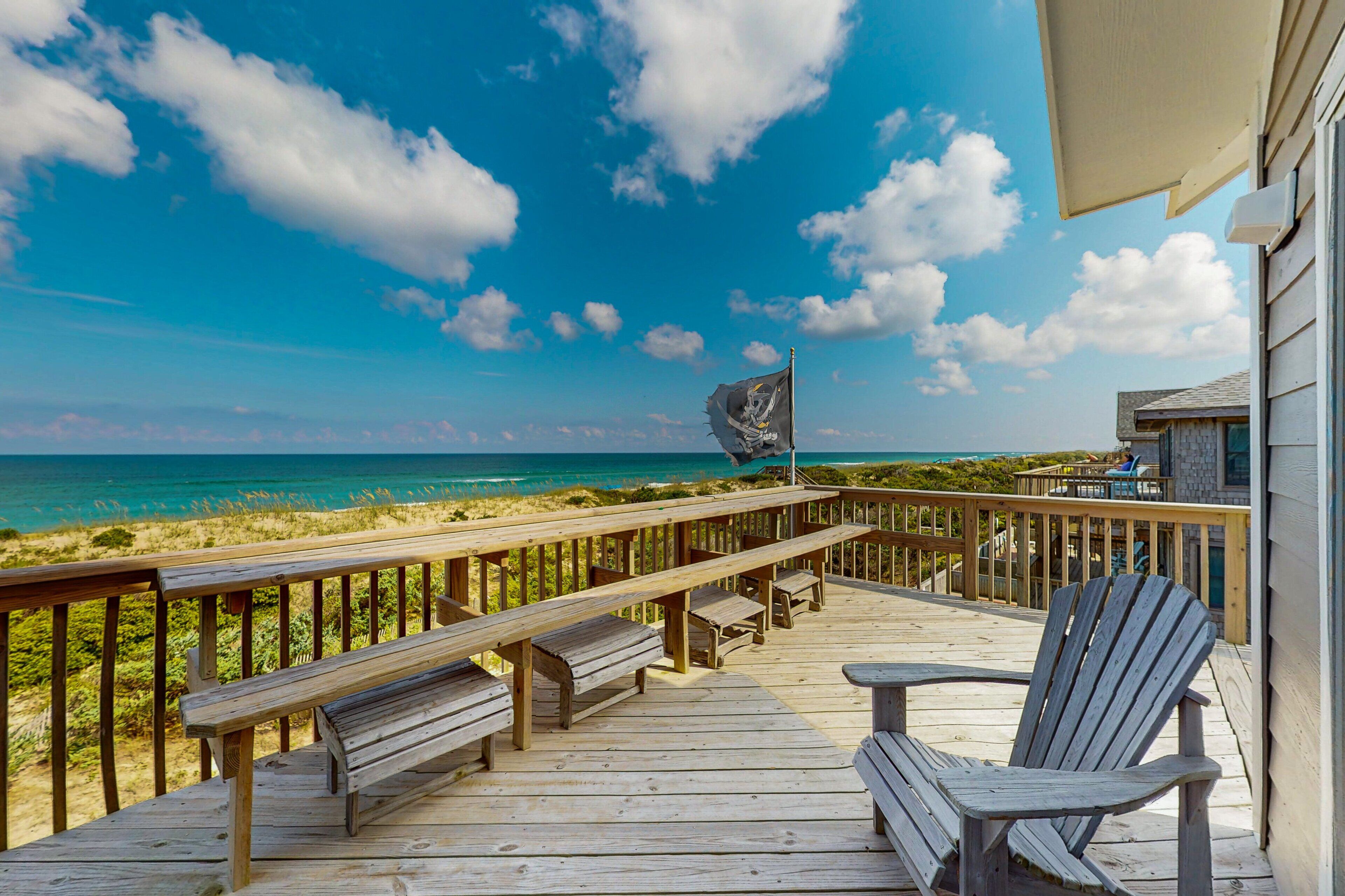 Une terrasse en bois avec des bancs et une chaise, donnant sur une plage.