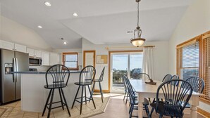 Une cuisine moderne dotée d’un îlot central, de tabourets de bar et d’une table à manger avec des chaises.
