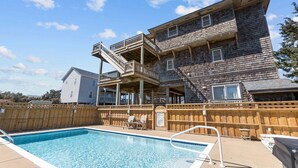Un bâtiment en bois doté d’une piscine, d’un espace extérieur aménagé et d’une clôture en bois.